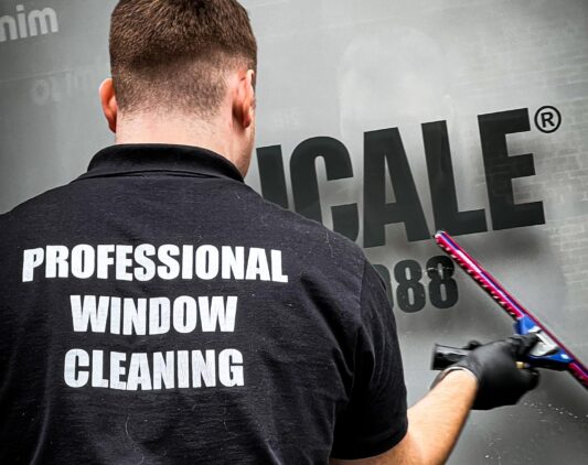 Professional window cleaner washing commercial storefront