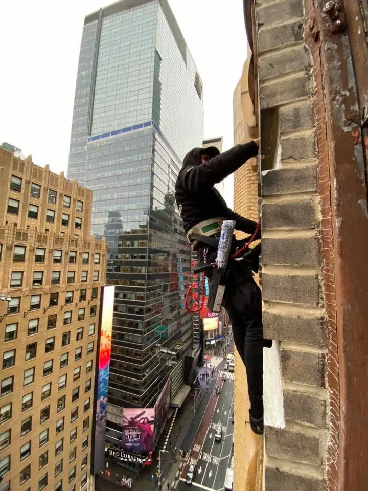 Advanced safety harnesses and high-tech cleaning tools laid out against the backdrop of a Manhattan high-rise, highlighting the essential equipment used by window cleaners to ensure safety and efficiency at great heights.