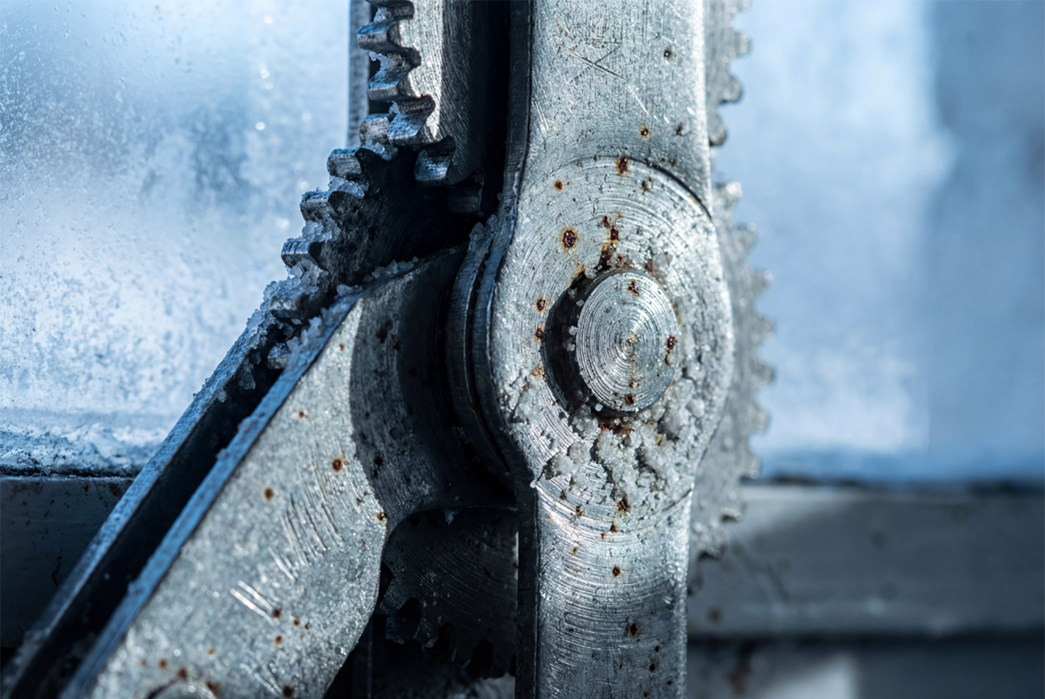Macro photography of a metal window hinge showing early signs of rust and white salt deposits caused by winter weather and neglect.