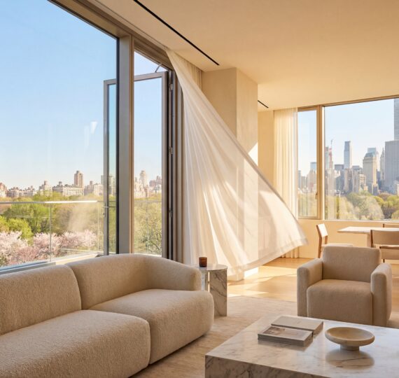 Luxury NYC penthouse interior with a floor-to-ceiling window cracked open, white curtains blowing in the spring breeze, and a view of the Manhattan skyline.