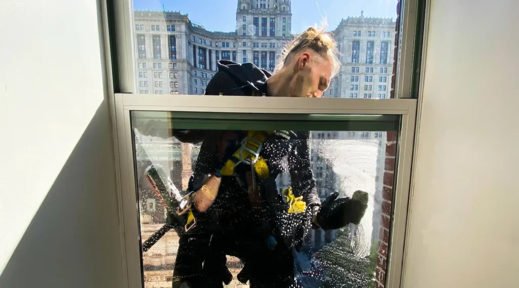 Big Apple Window Cleaning company technician cleaning a high rise window from outside
