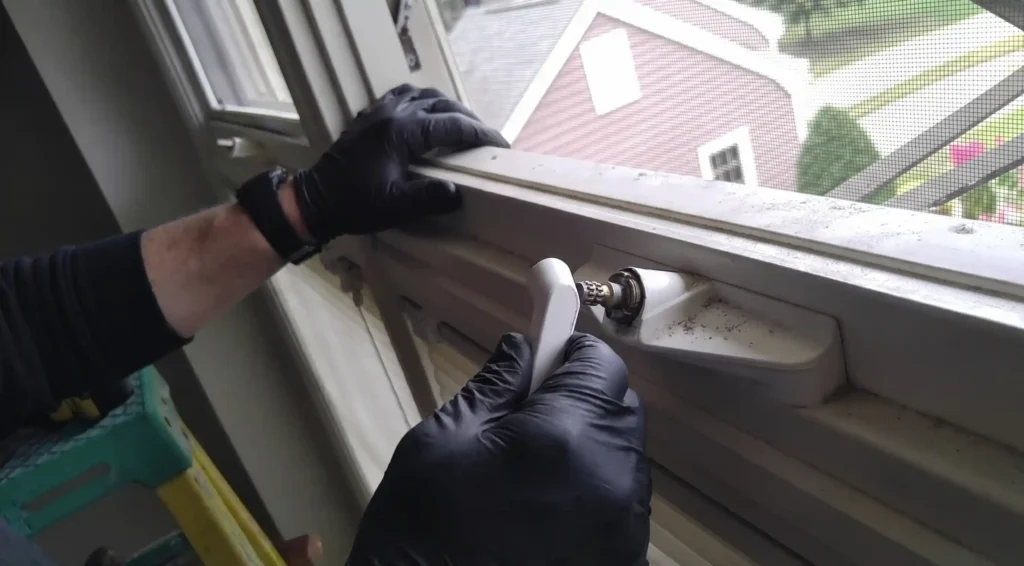 Big Apple Window Cleaning company technician removing a casement window crank handle during repair