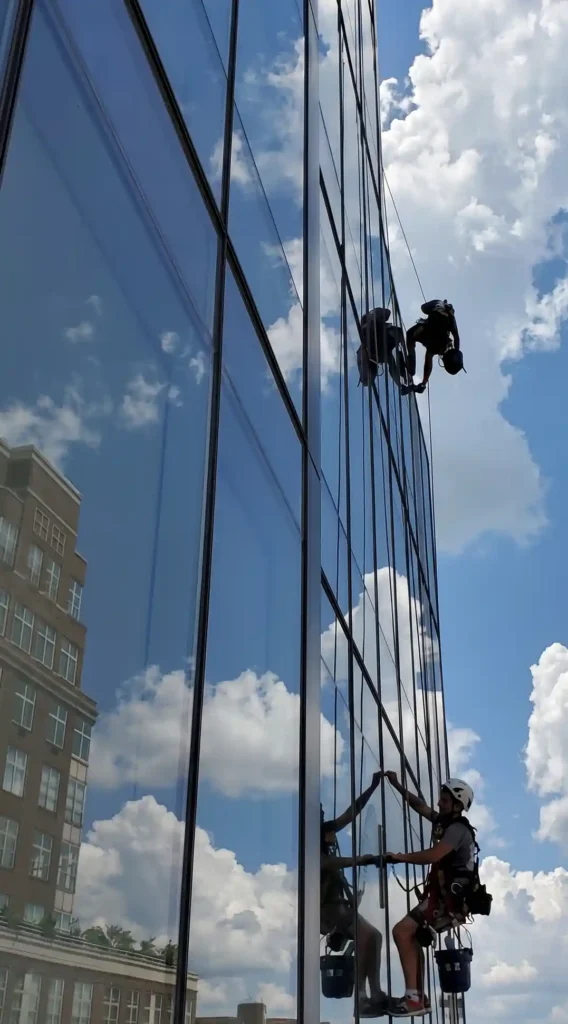 Rope access technicians cleaning glass facade on a high rise building