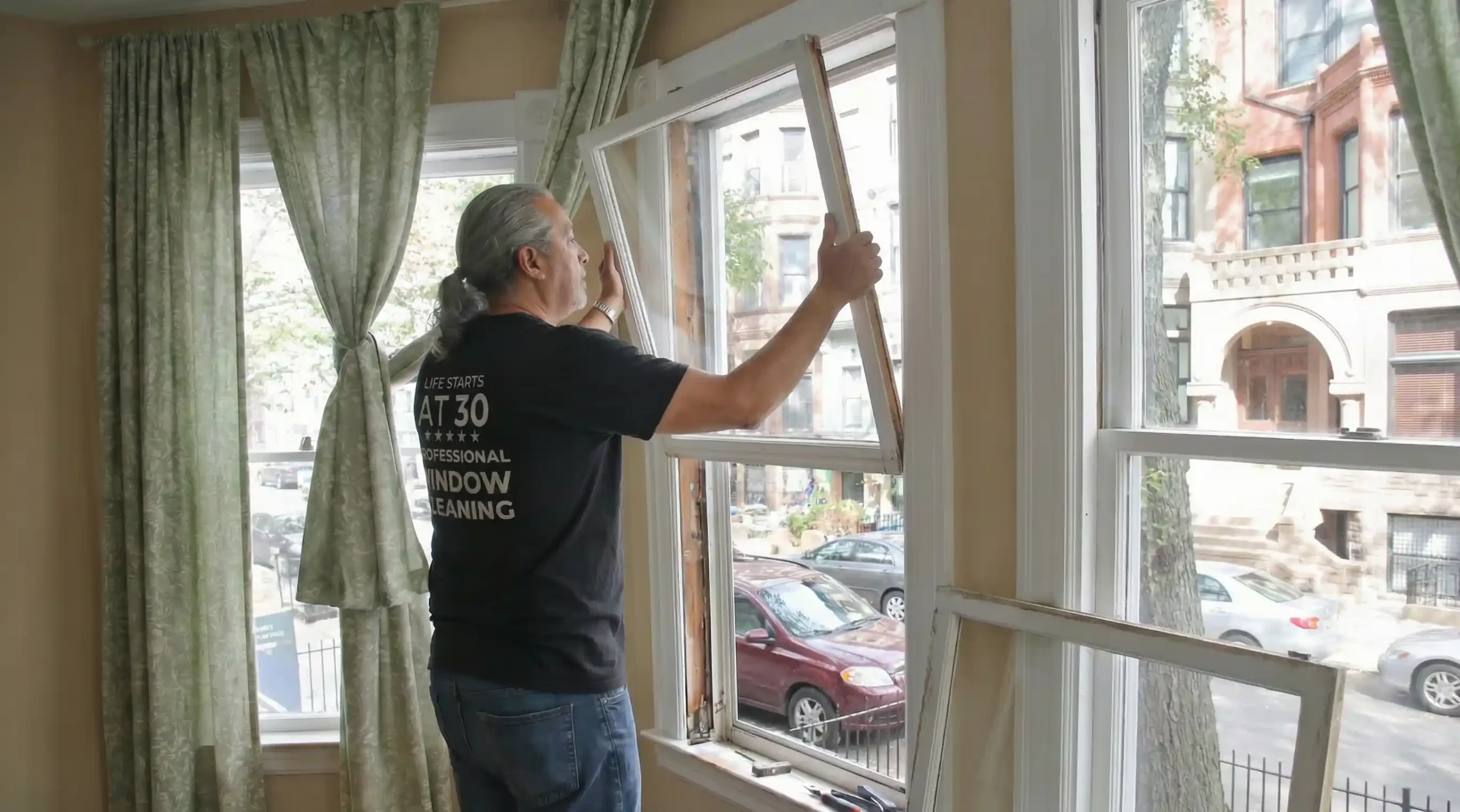 Big Apple Window Cleaning company technician removing a window sash for spring replacement in an NYC apartment