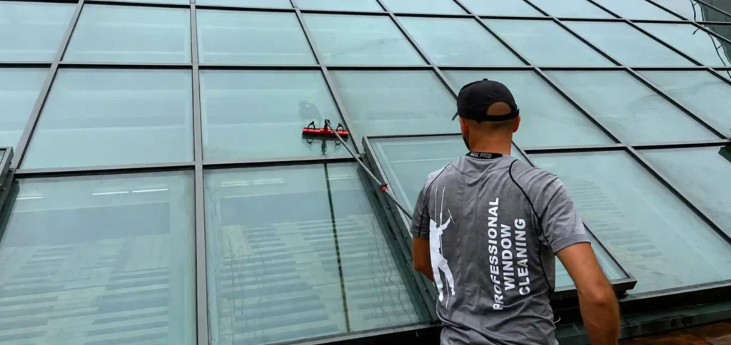 Technician cleaning sloped atrium glass as part of a corporate building window cleaning program