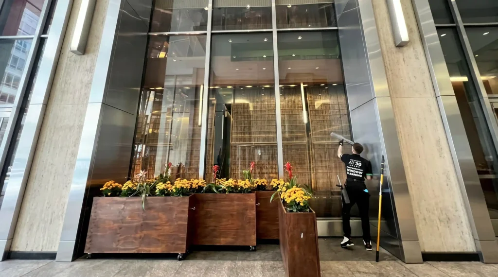Big Apple Window Cleaning company technician washing large commercial lobby glass panels in New York