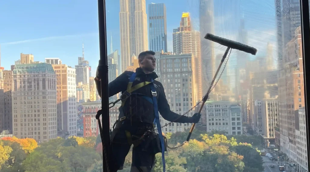 Technician cleaning high rise windows during scheduled building maintenance in Manhattan
