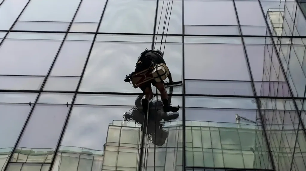 Rope access technician cleaning windows on a high-rise glass facade