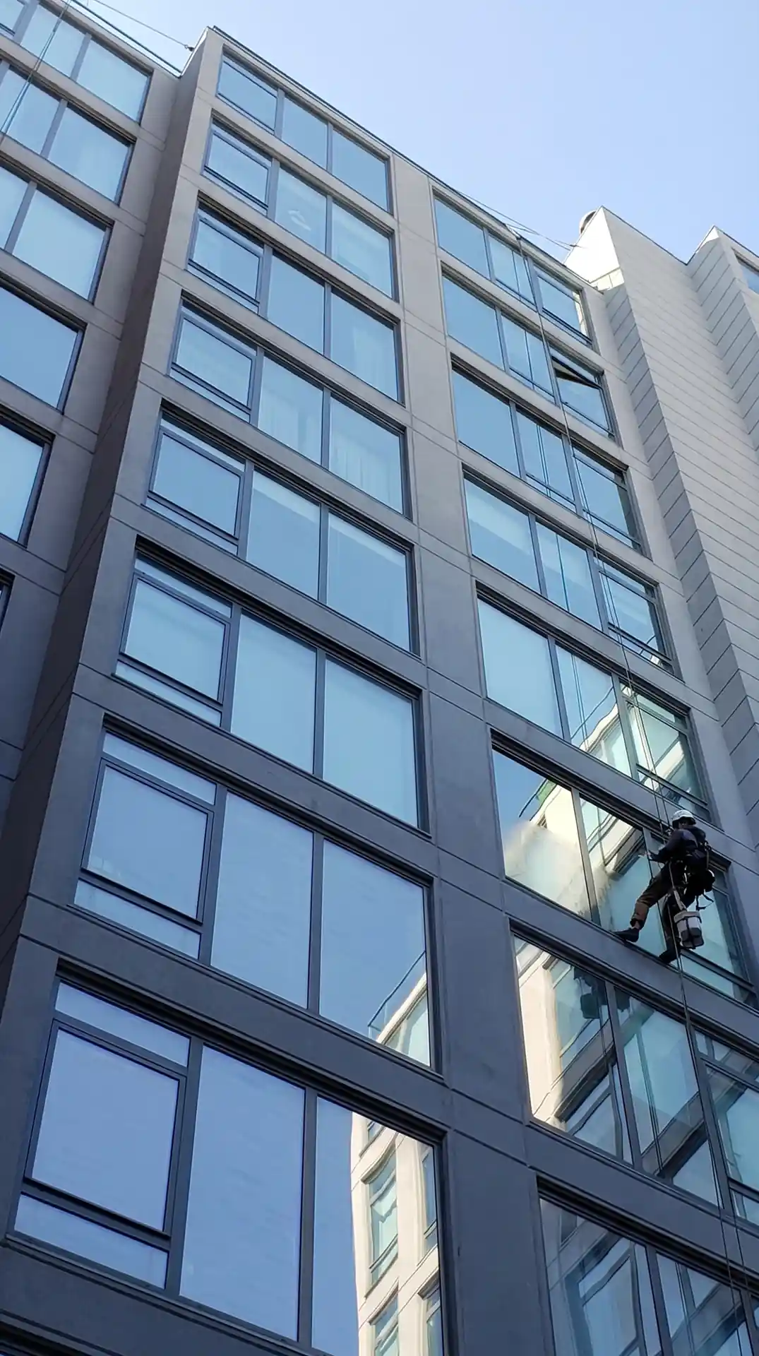 Rope access technician cleaning windows on a residential high-rise building