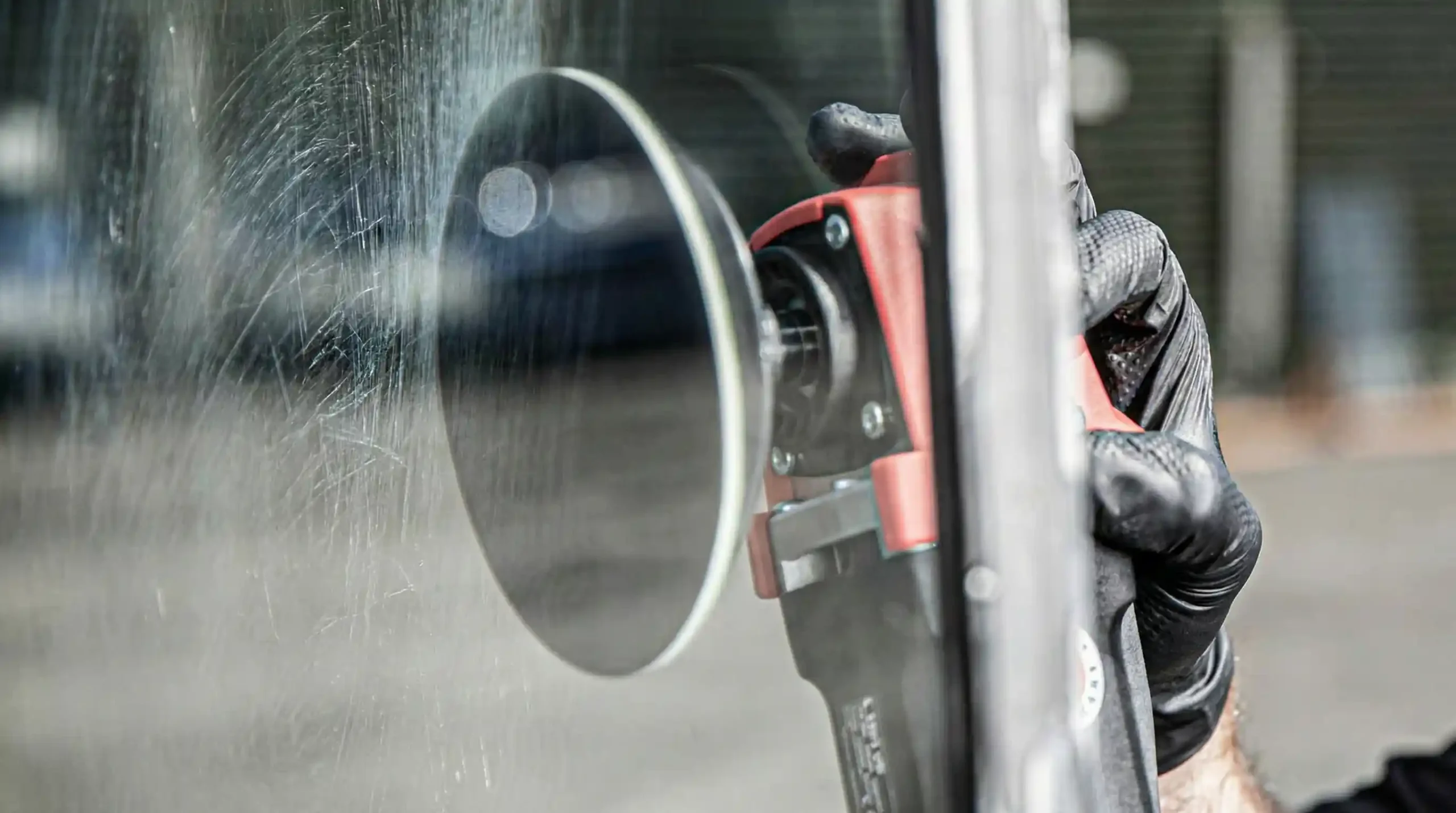 Technician using a rotary polisher to remove scratches from glass during professional glass scratch removal