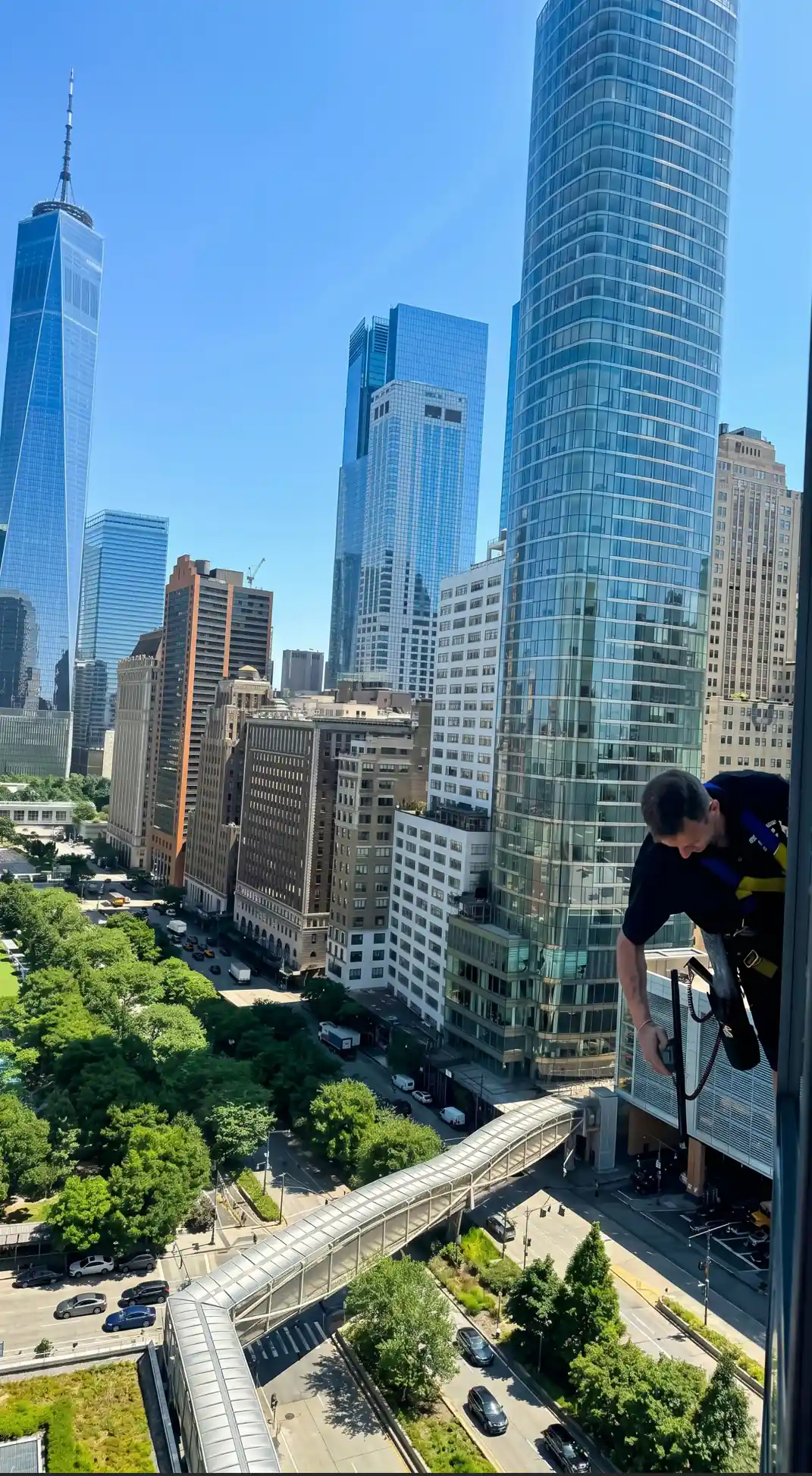 High-rise window cleaning technician working above Lower Manhattan during scheduled building maintenance