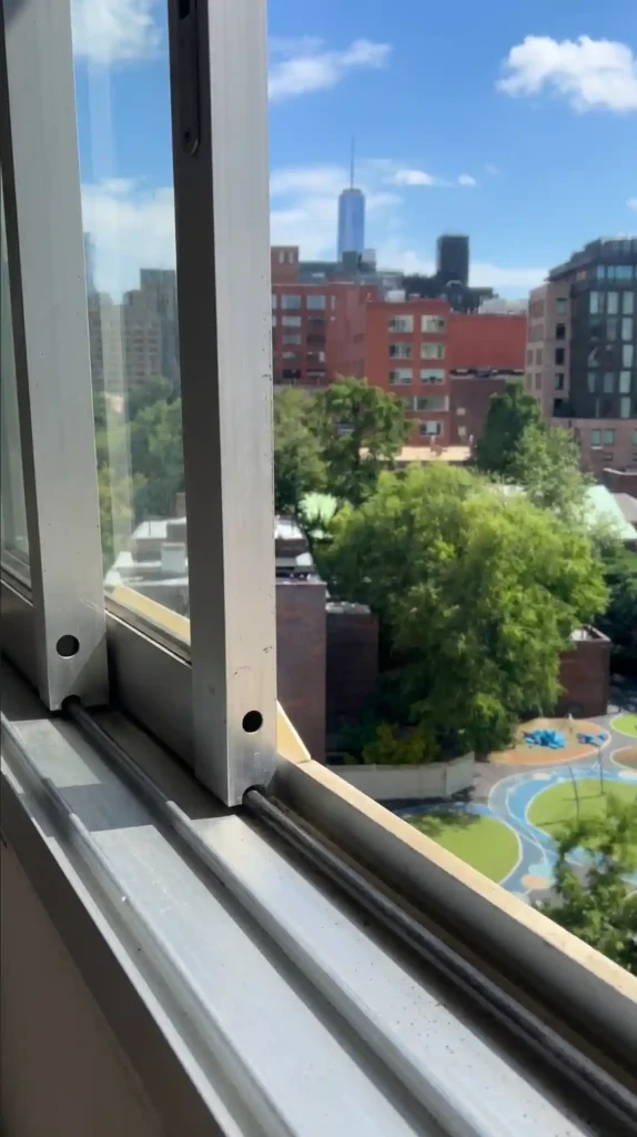 Close-up of a sliding window track and frame in a Manhattan apartment with city skyline view