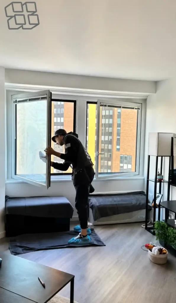 Technician cleaning an open apartment window with cloth during interior glass cleaning