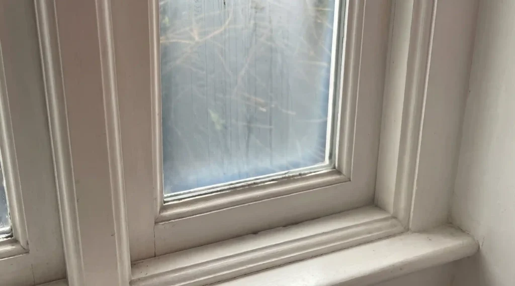 Old house window with foggy glass and worn frame before repair or replacement